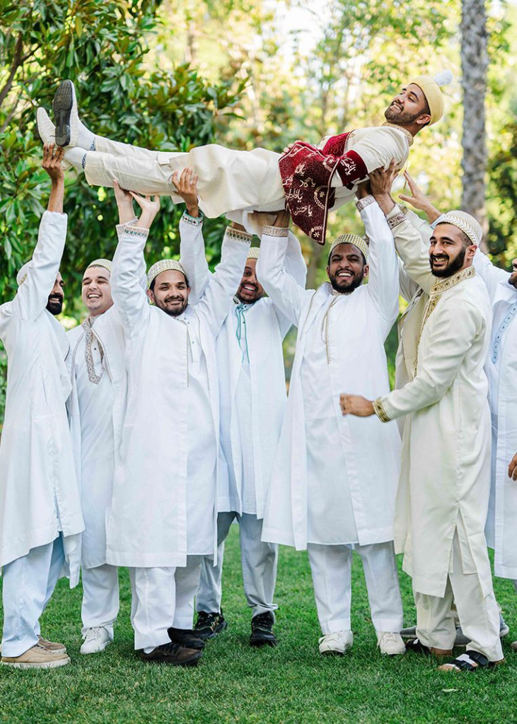 Groomsmen lifting the groom in the air, celebrating.