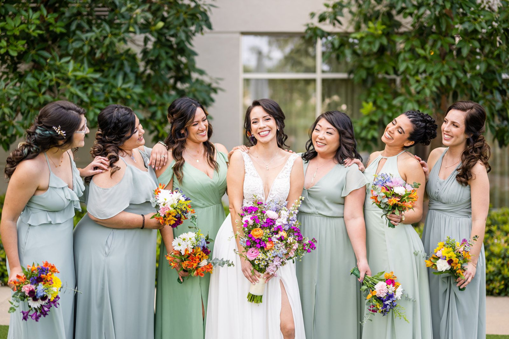 Bride with bridesmaids standing behind her in a supportive, 'we’ve got your back' pose.
